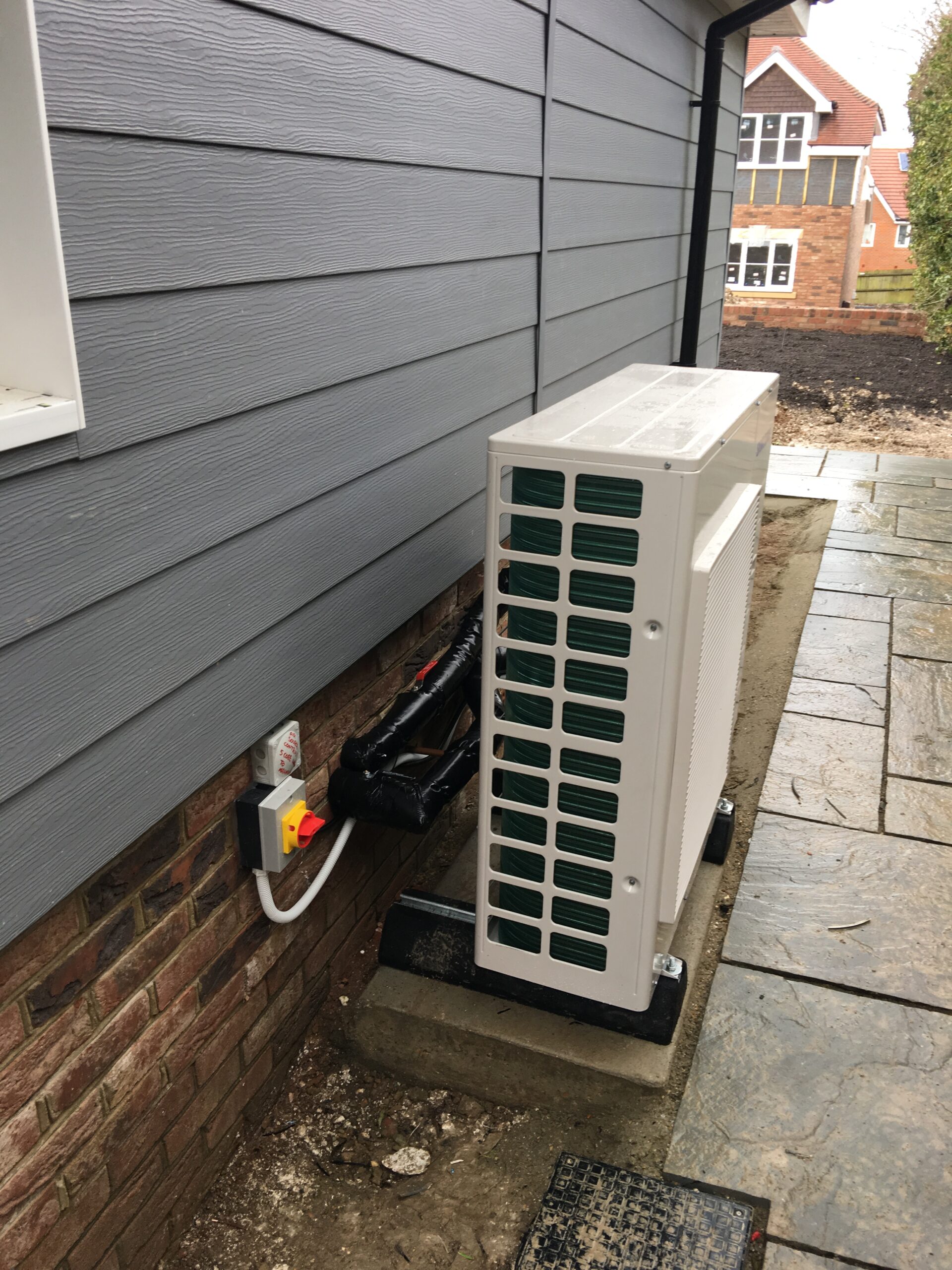 Air source heat pump installation beside garden patio